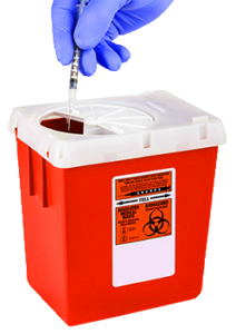 A gloved hand disposing of a syringe into a red medical sharps disposal container with biohazard symbol.