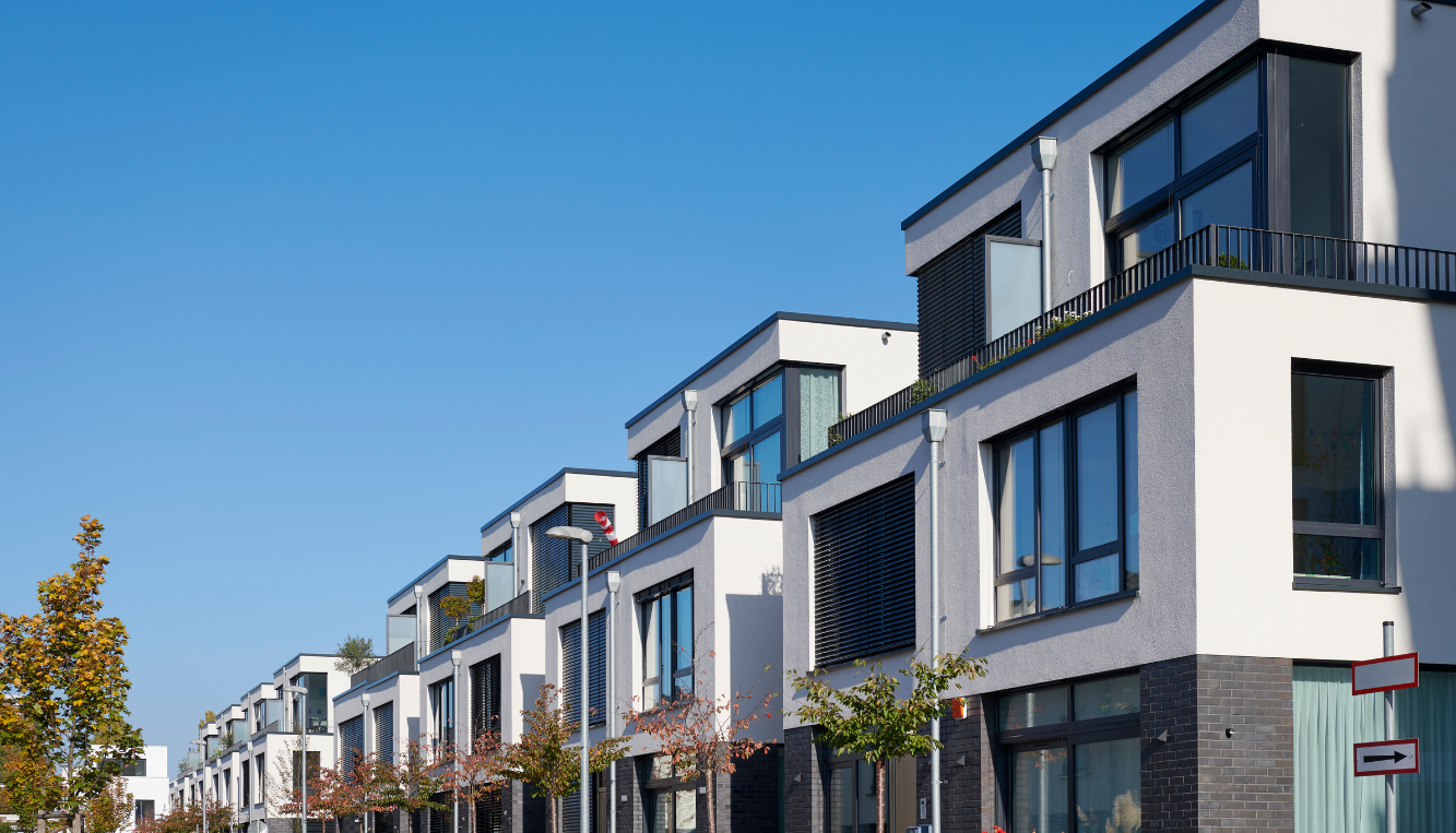 Row of modern townhouses with trees and blue sky in the background.