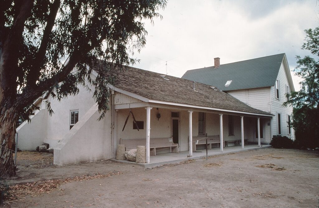 Side view of Strathearn home showing porch and adobe architecture, 1978.